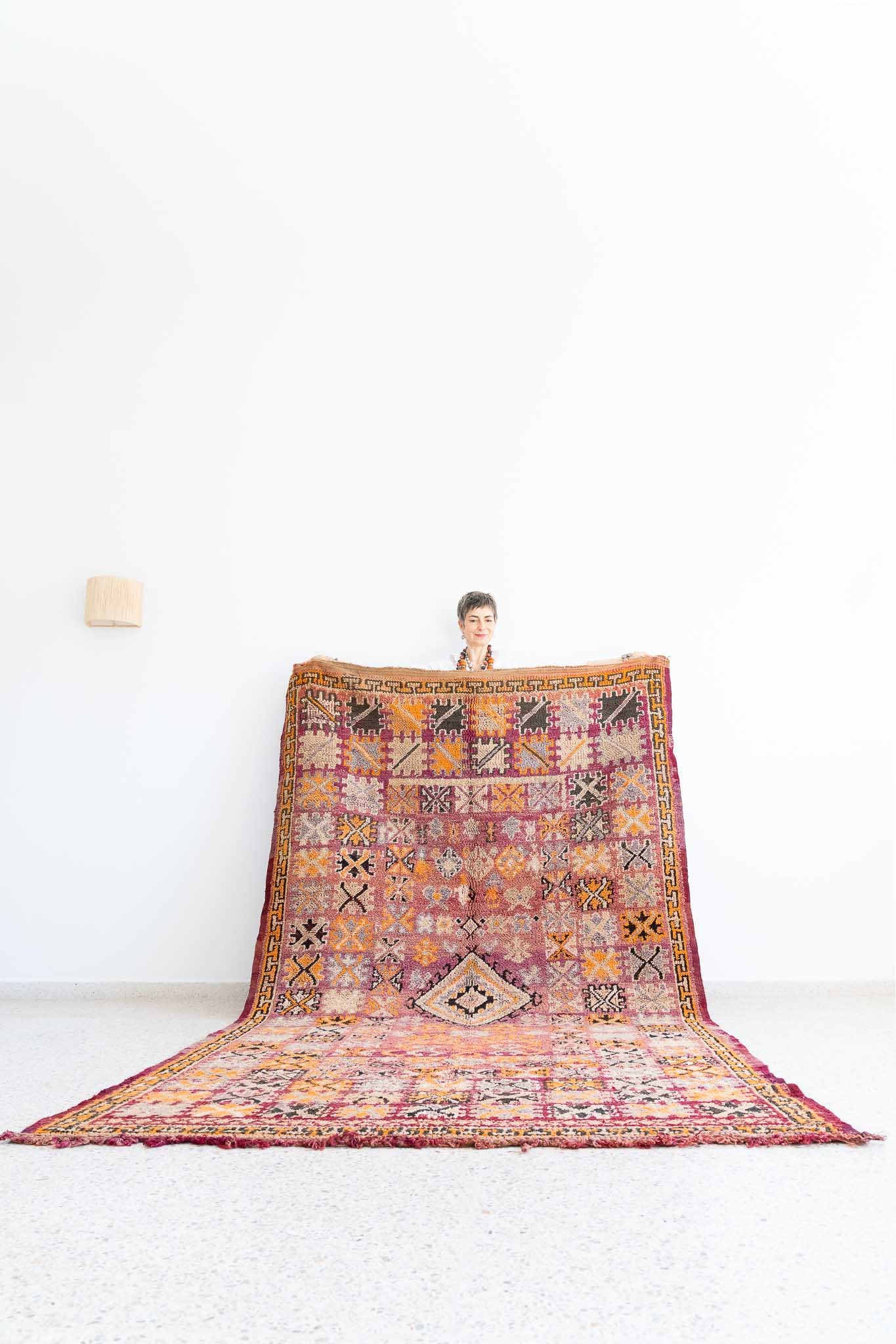 Vintage Moroccan rug. It is may be a Boujaad or from a Act Yacoub tribe.Beautiful intricate design in faded colors. The faded color scheme is breathtaking, with a rosy background that fades into ivory and orange, as well as dark and light gray for the succession of square patterns repeated all over the composition. 